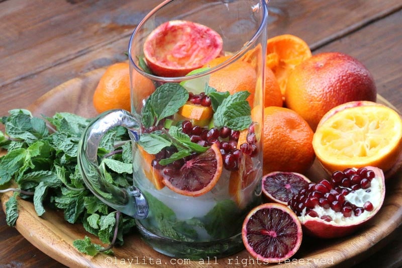 Add the arak or anise liqour, ice cubes, citrus slices, pomegranate arils, and additional mint