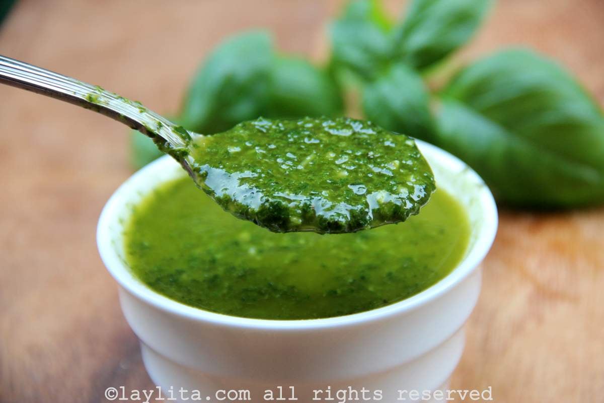A bowl of basil oil sauce in a white ramekin with a spoon showing the sauce