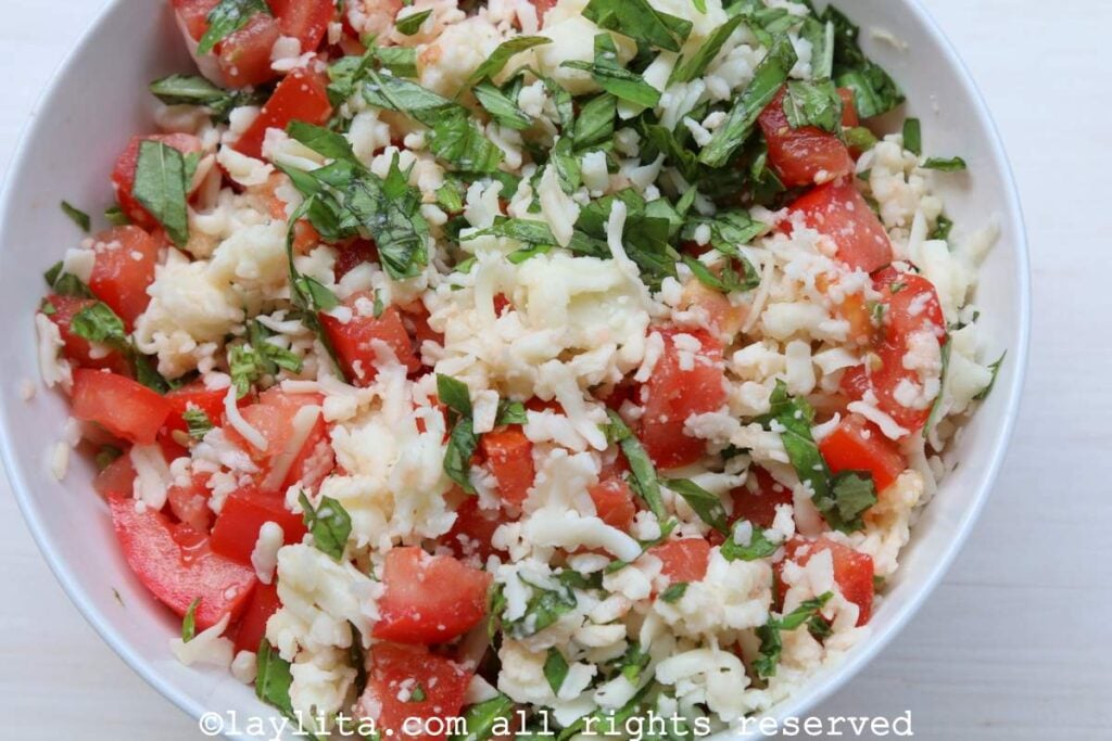 Caprese empanada filling of cheese, tomato and basil in a white bowl