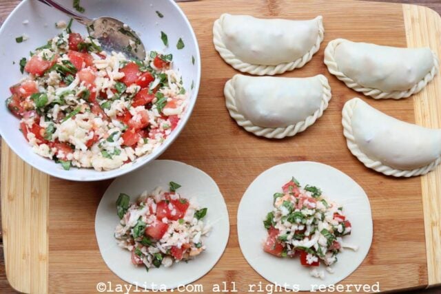 Filling the caprese empanadas and assembling them on a cutting board