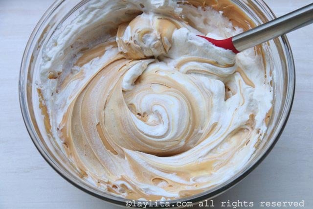 Use una cuchara para incorporar la crema batida a la mezcla del mascarpone y dulce de leche