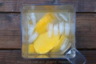 Ponga los trozos o la pulpa de mango, el jugo de limón, agua, azúcar, tequila picante, licor de naranja, y hielo en la licuadora.