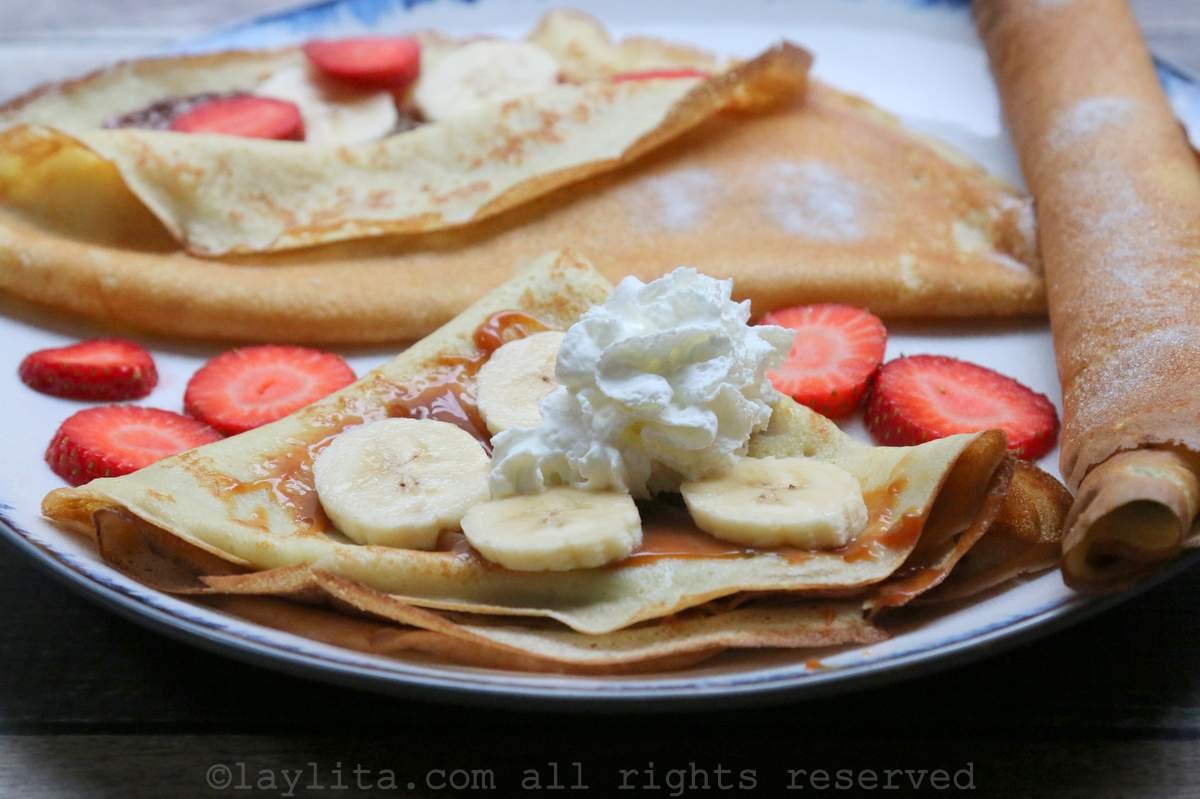 Close up of crepes filled with bananas, strawberries and whipped cream