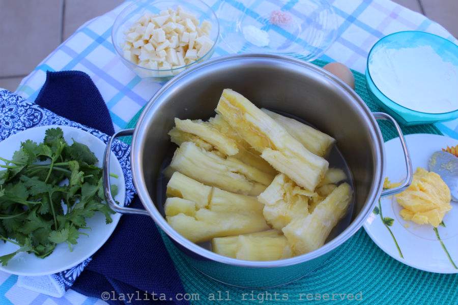 Ingredients for Brazilian fried yuca balls or bolinhos de macaxeira on a round table with a white and blue tablecloth