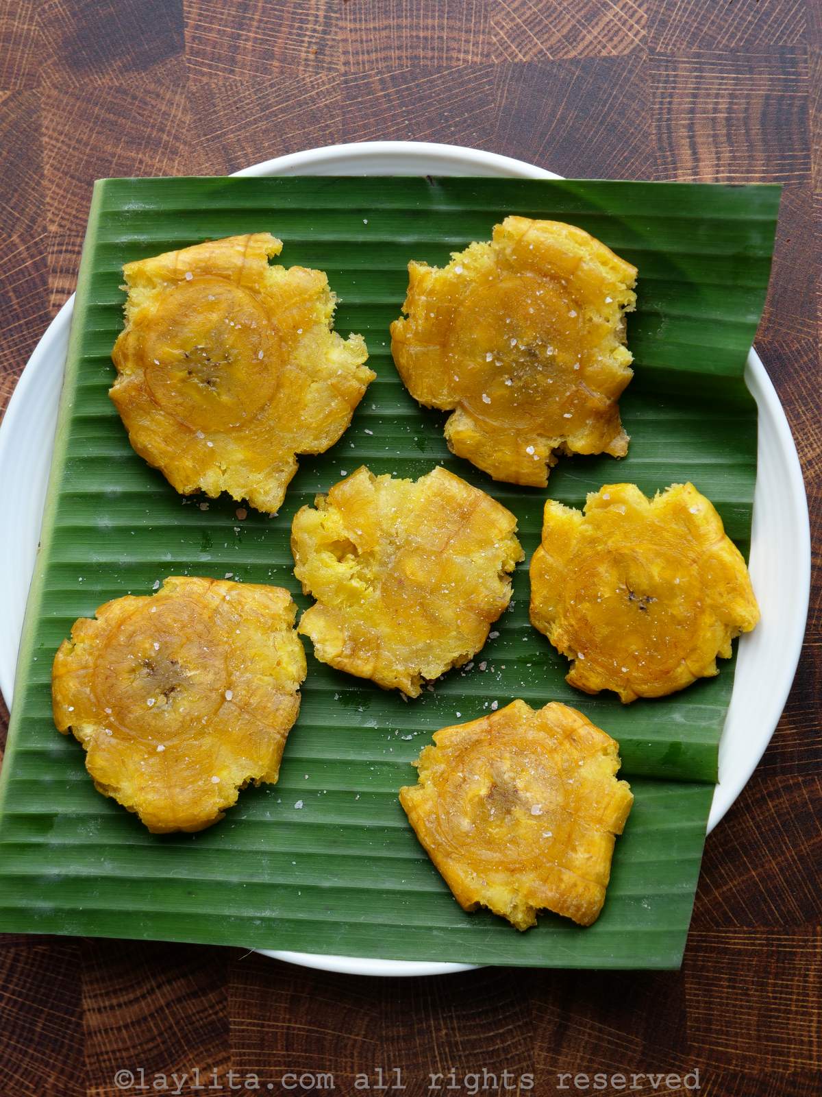 Patacones, tostones or double fried green plantains on top of a banana leaf