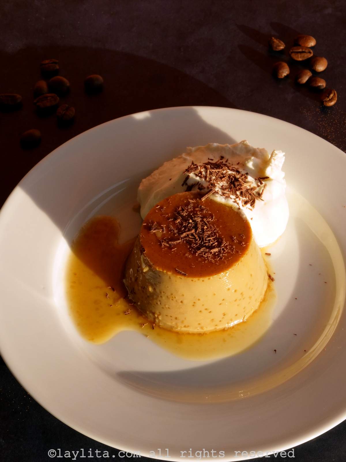 Coffee flan with whipped cream on a white plate in the sunlight