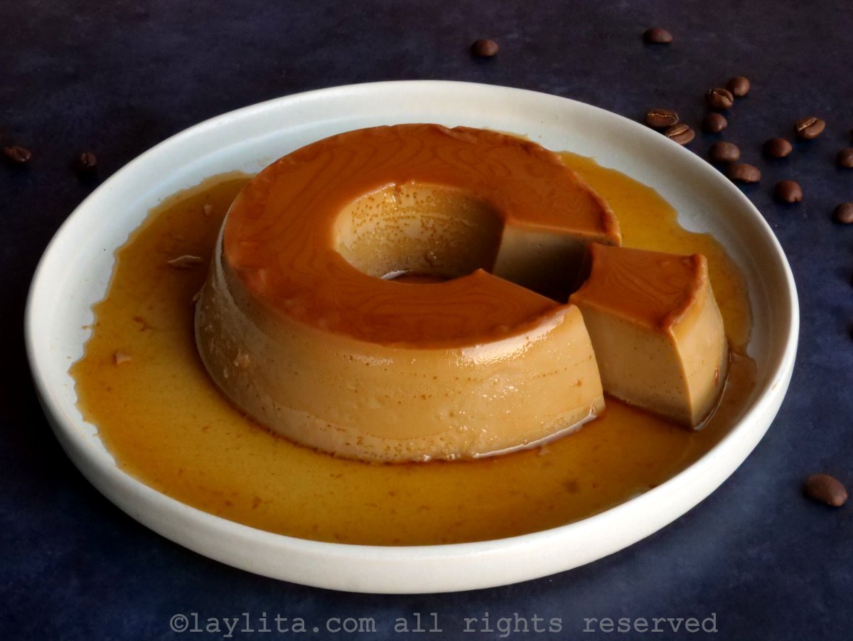 Coffee flan on a white plate with one slice taken slightly out of the circle of flan.