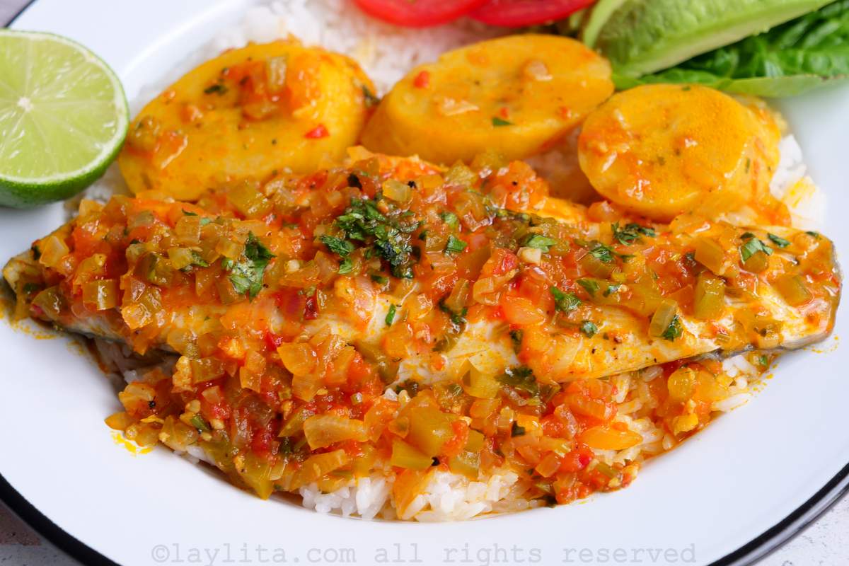 Fish served on a white plate with plantains and avocado