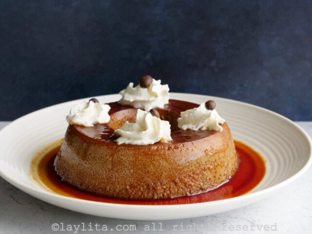 Large flan served on a plate with four dollops of whipped cream on top