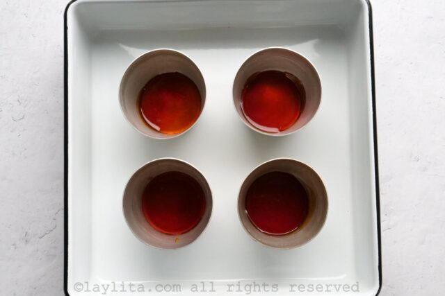 Four ramekins with caramel in the bottom