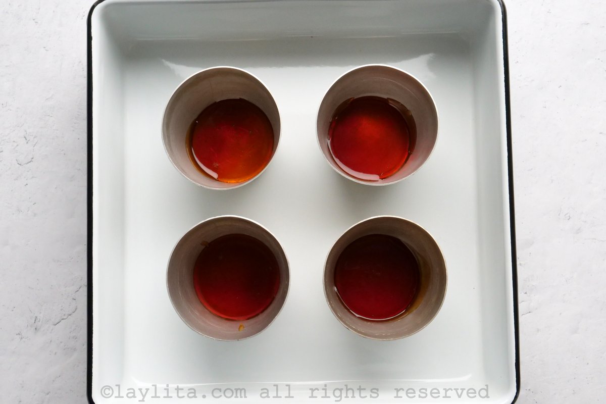 Four ramekins with caramel in the bottom
