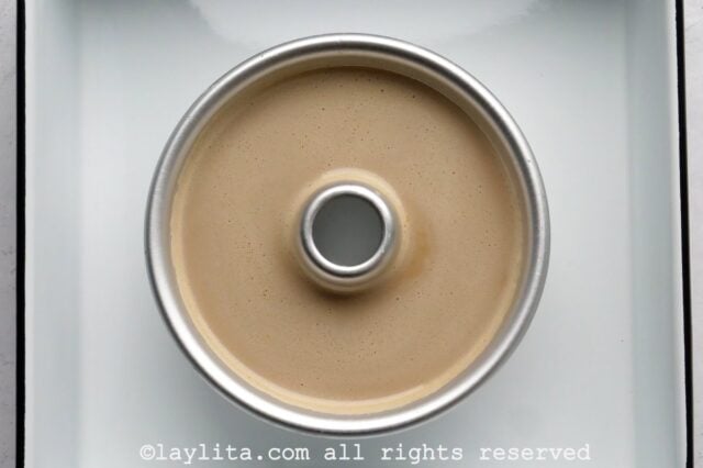 Large coffee flan in a baking mold inside a water bath