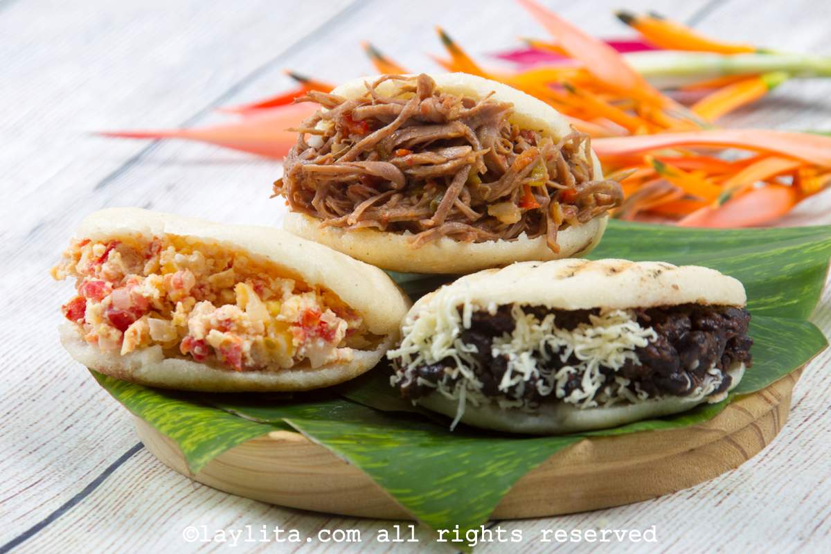 A plate with arepas or corn patties filled with carne mechada, black beans and scrambled eggs