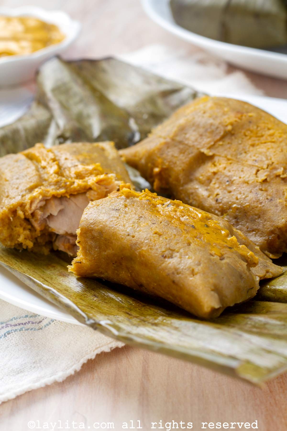 Photo of two bollos served on a plate with one of the opened to show the fish in the middle