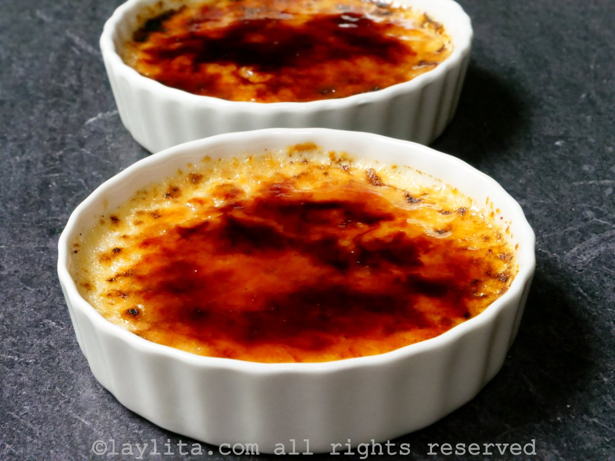 Two ramekins of creme brulee with a caramelized topping.