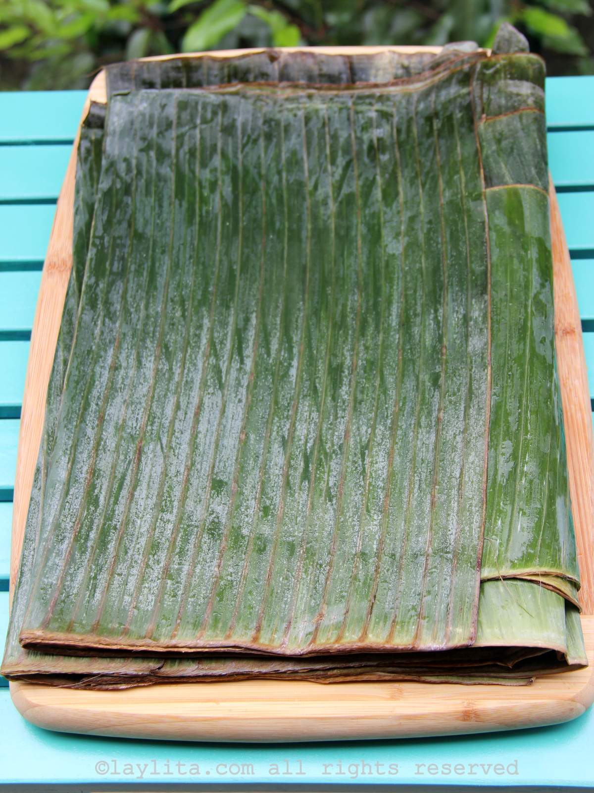 Banana leaves or plantain leaves on a board on top of a blue table