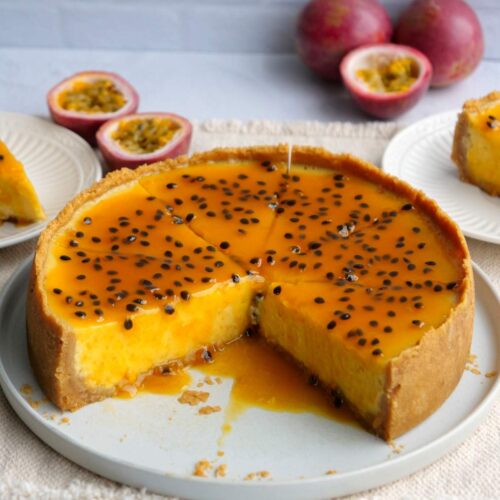 Overhead shot of passion fruit cheesecake on a serving dish with two pieces missing.
