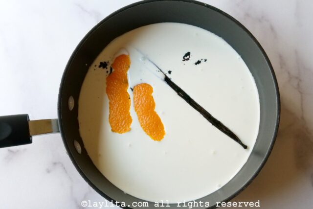 Cream in a saucepan with orange peels and full vanilla pod.