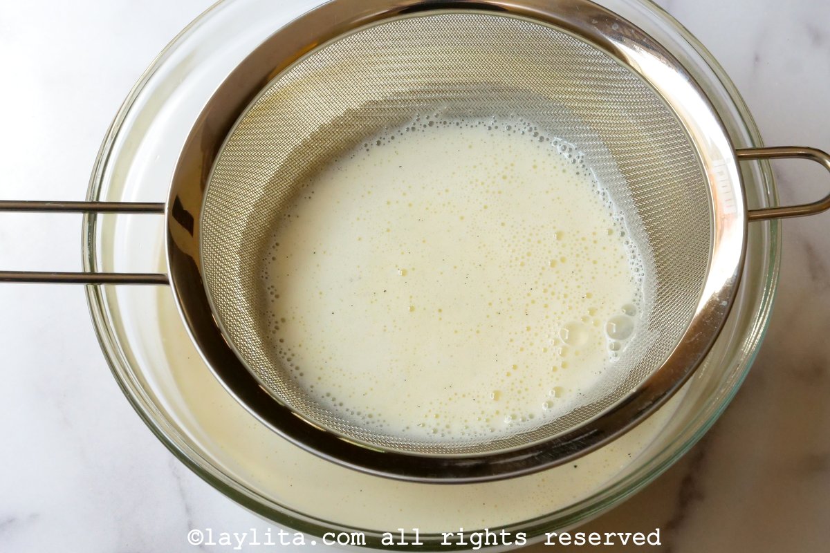 Mesh strainer over a bowl with the creme brulee mixture going through it.