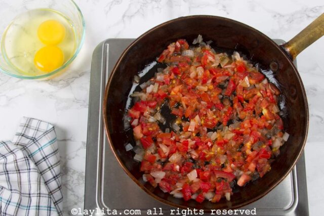 A skillet with onions and tomatoes