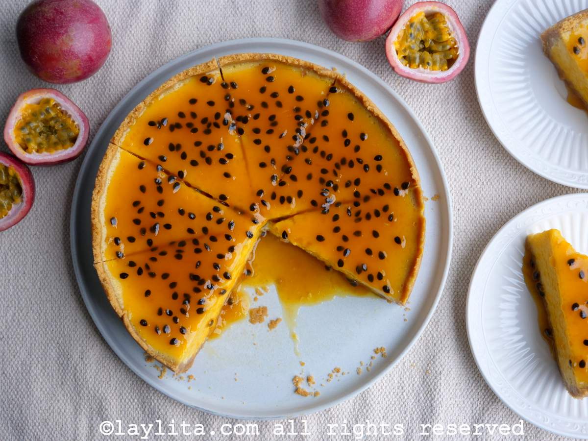 Overhead shot of passion fruit cheesecake with sauce on top and cut into slices.