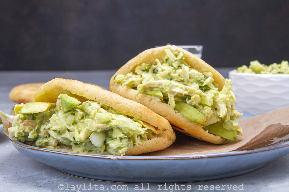 Two arepas on a plate filled with avocado chicken salad.