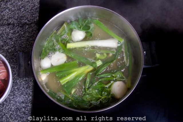 Water in a large pot with vegetables and herbs
