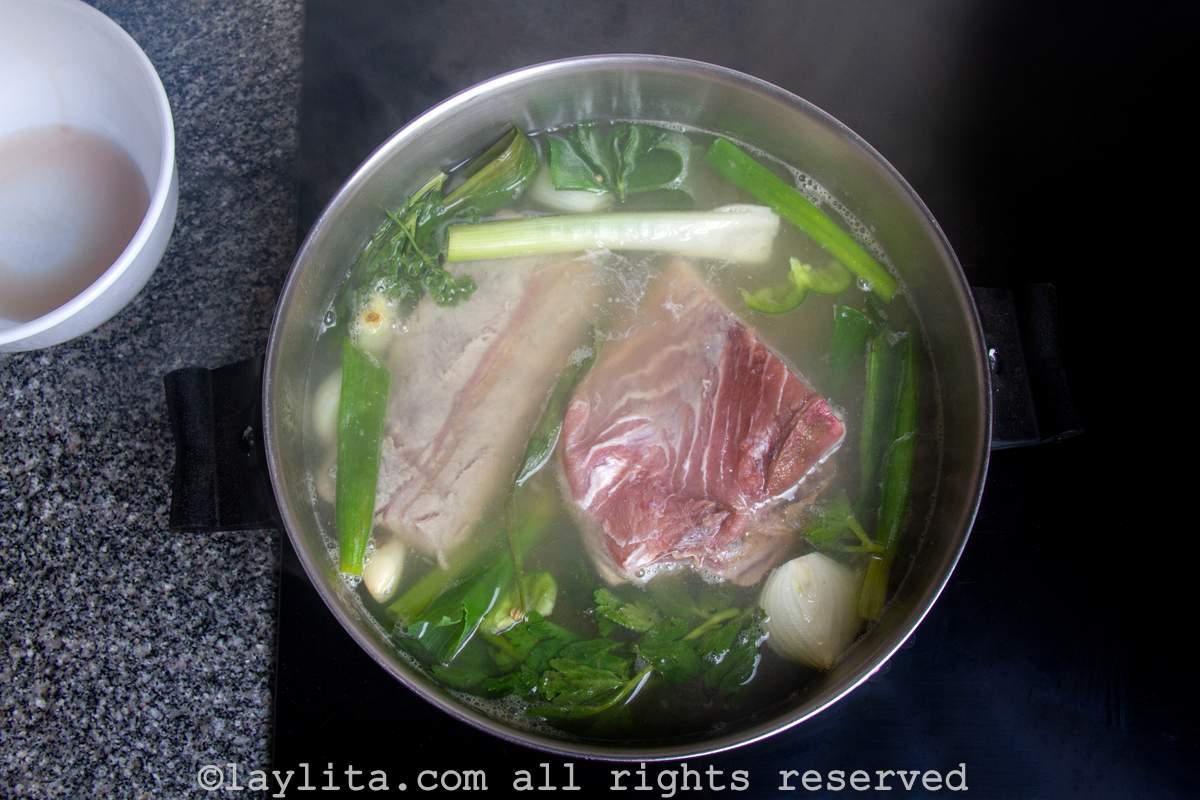 Water in a large pot with vegetables, herbs and fish.