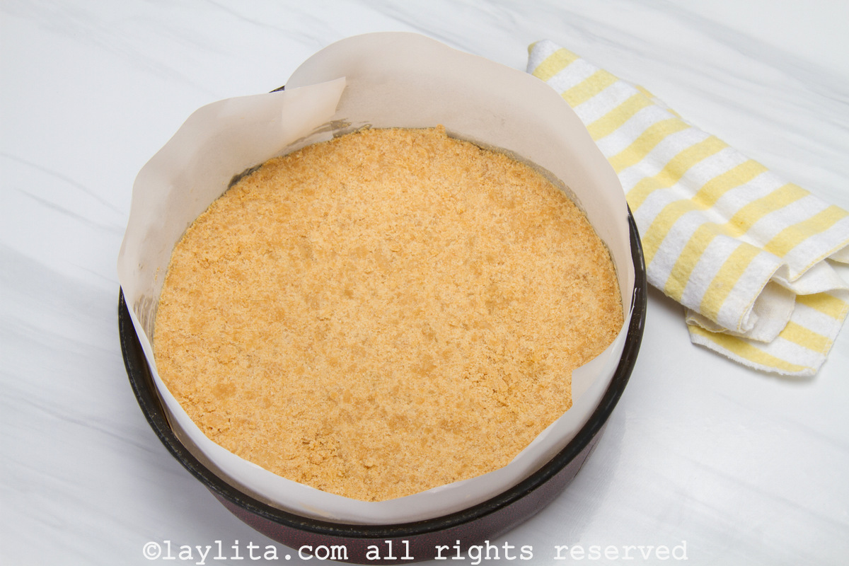 Cookie crust in the bottom of a parchment paper lined spring-form pan.