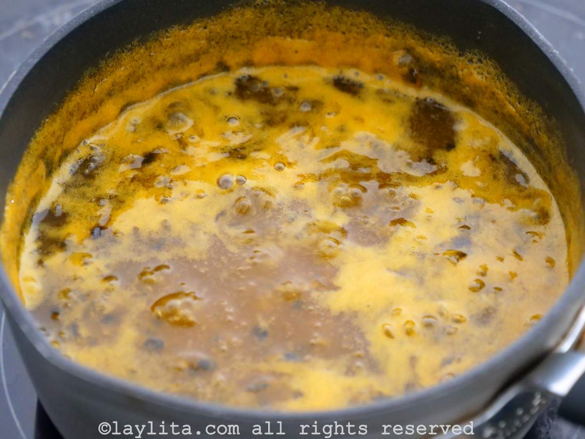 Passion fruit juice and sugar simmering in a saucepan.