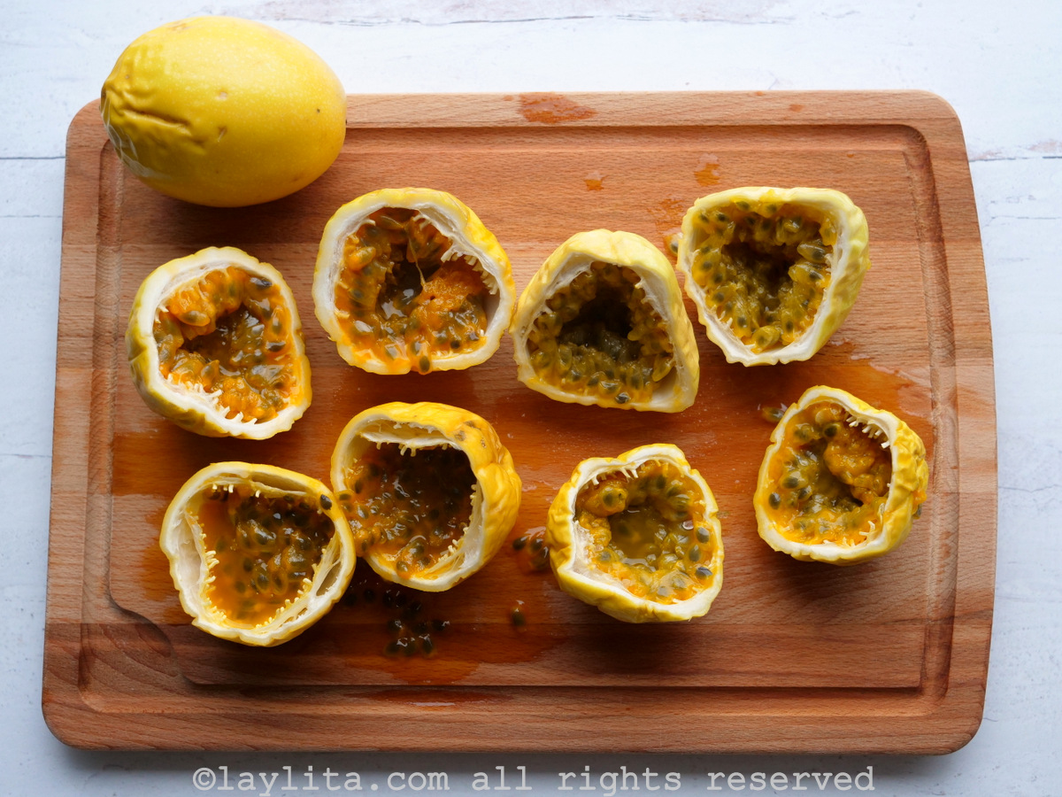 Yellow passion fruit halves placed on a wooden cutting board.