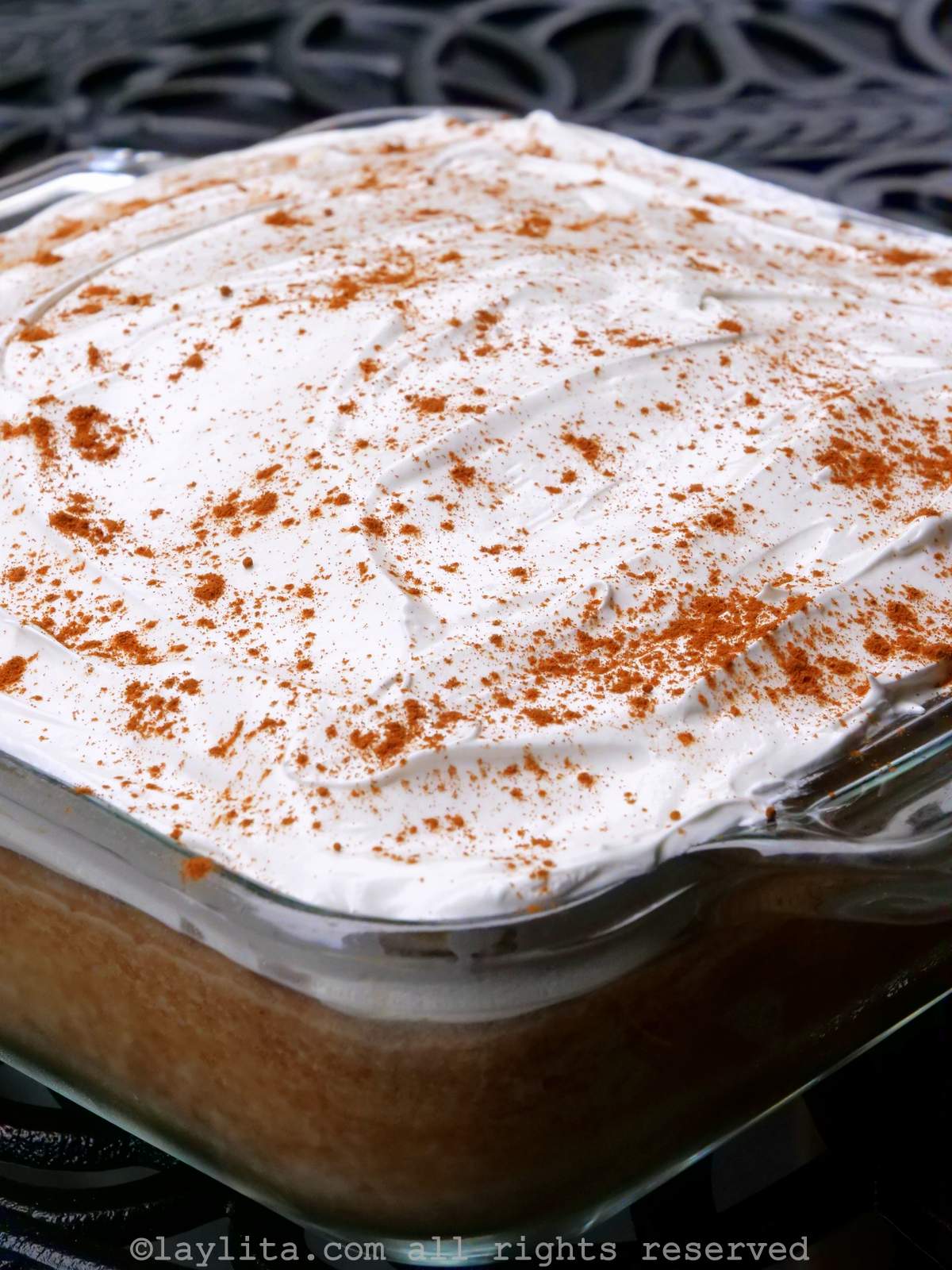 Torta tres leches cake in a square baking pan decorated with frosting and cinnamon