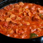 Close up of sausage rougail stew or rougaille saucisse in a cast iron pan.