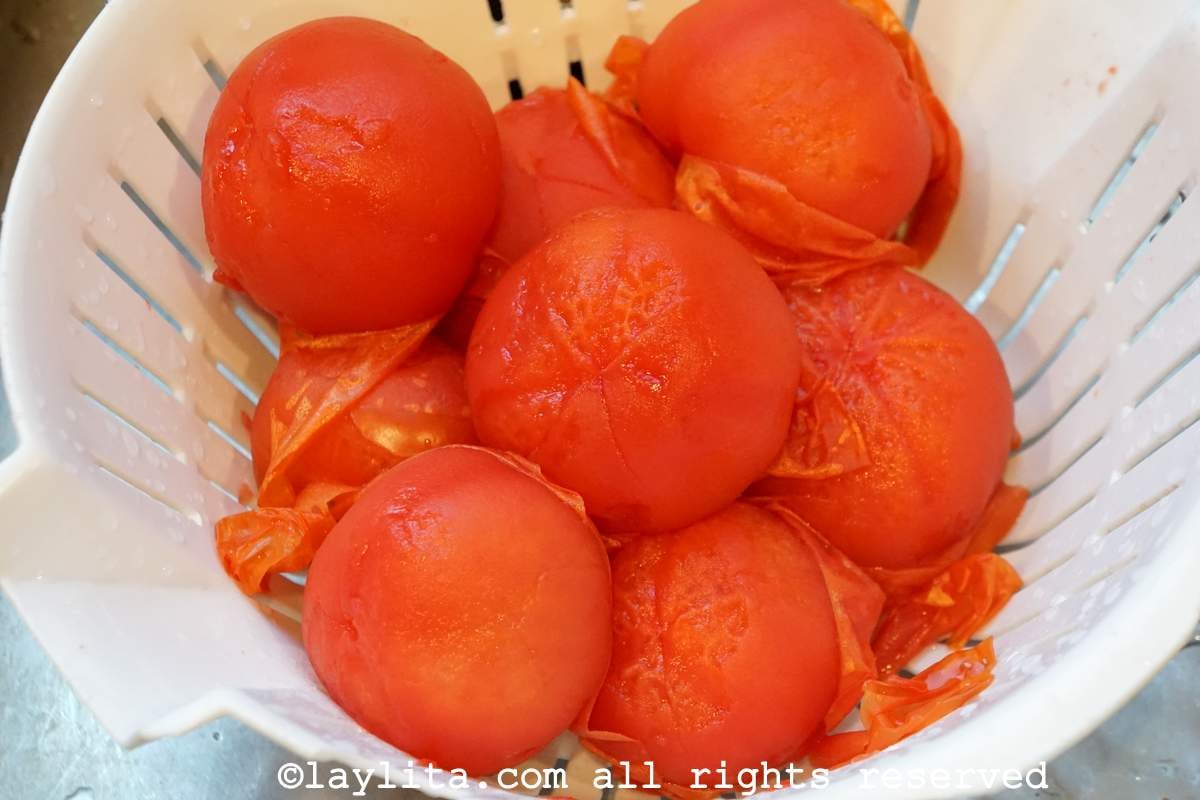 Tomatoes in a colander after being simmered with the peels starting to come off.