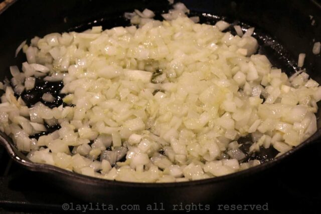 Onion and garlic sautéing in a skillet with olive oil.