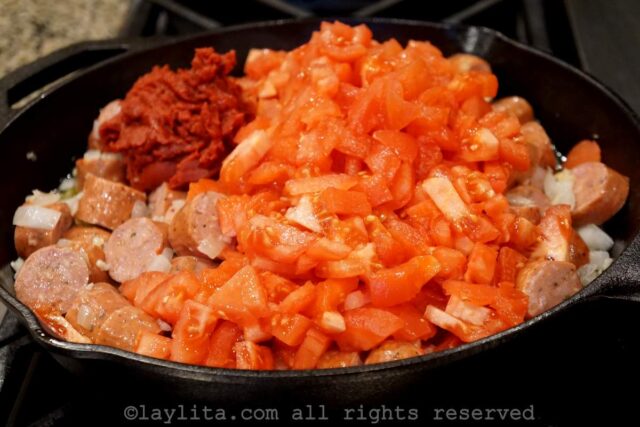 Sausages, tomatoes and tomato paste added to the skillet.