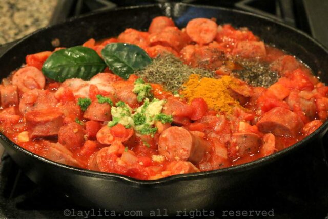 Spices and seasonings added to the tomato sausage mixture in the skillet.
