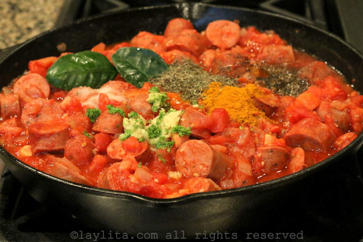 Spices and seasonings added to the tomato sausage mixture in the skillet.