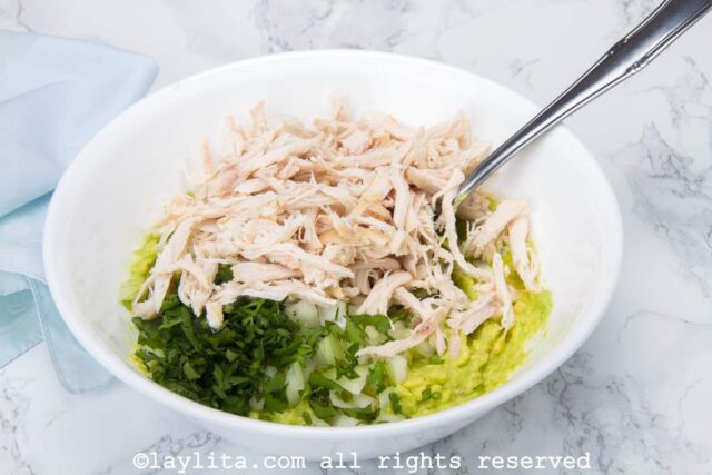Avocado chicken salad mixture in a white mixing bowl.