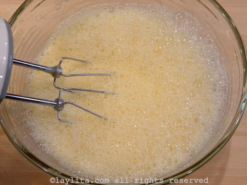 Quesillo mixture in a mixing bowl after being whisked with an electric mixer.
