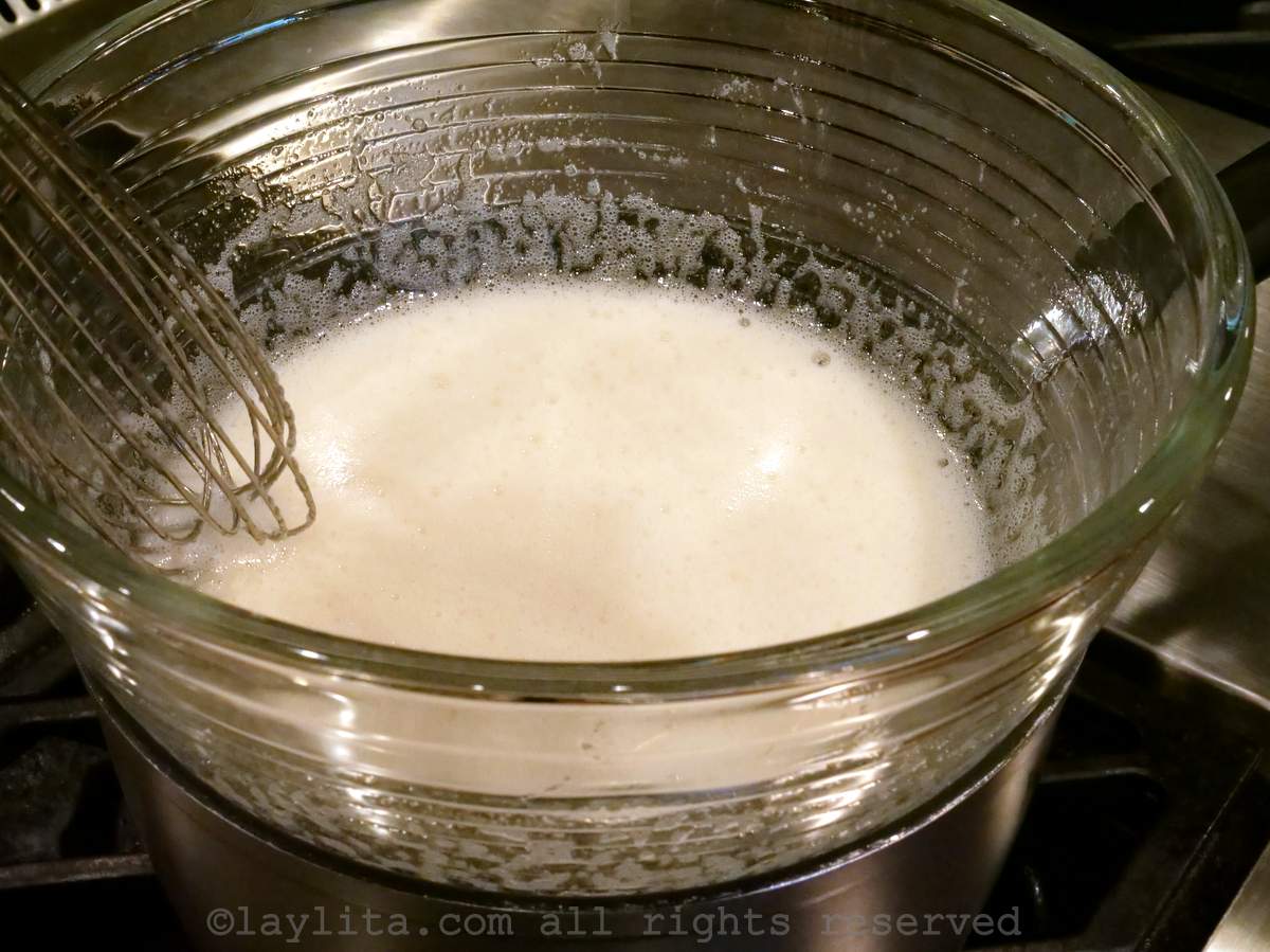 Whisking eggs and sugar in a mixing bowl over a saucepan of simmering water.