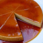 Quesillo (or flan) with caramel sauce on top served on a plate with one slice missing.
