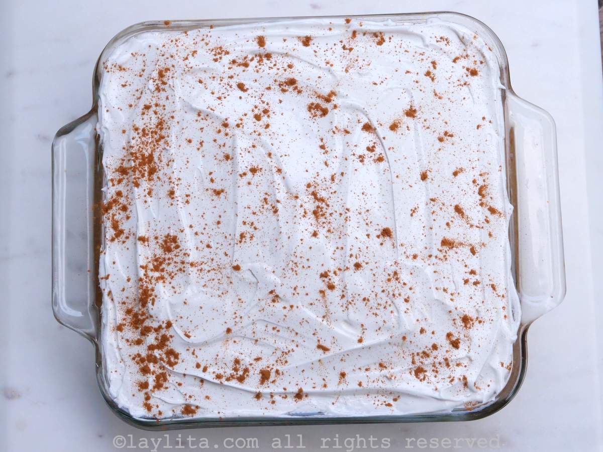 Tres leches cake with a white frosting and cinnamon sprinkled on top.
