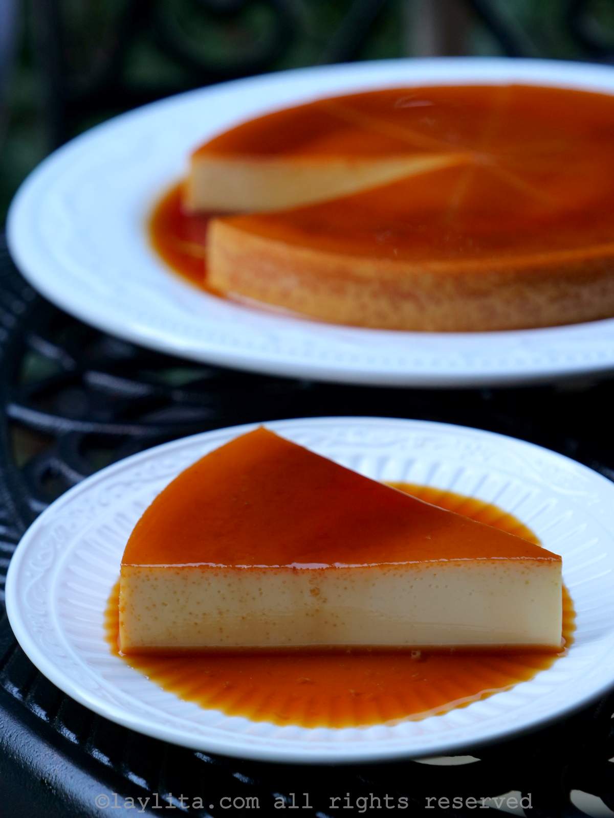 Slice of Venezuelan flan or quesillo on a plate with the rest of the flan on a plate behind it.