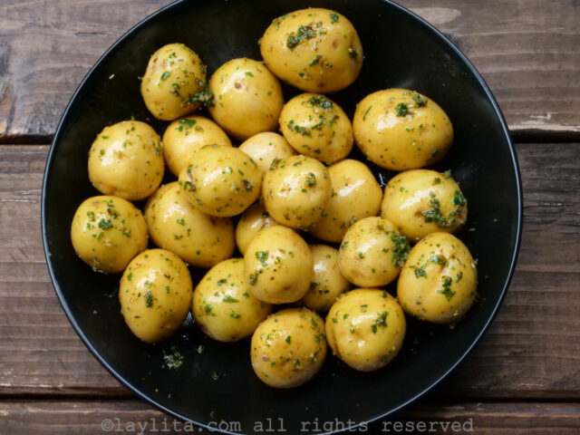 Baby potatoes in a black bowl coated in chimichurri.