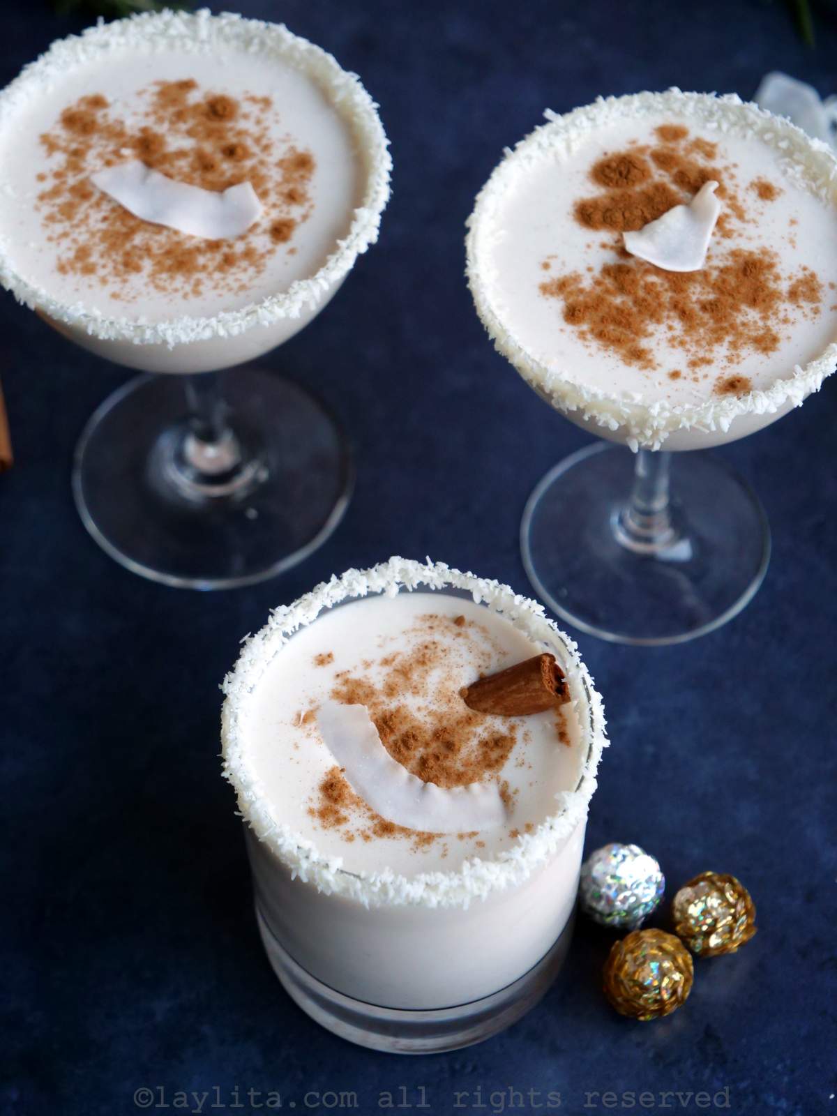 Three glasses of Puerto Rican eggnog or Coquito on a blue background