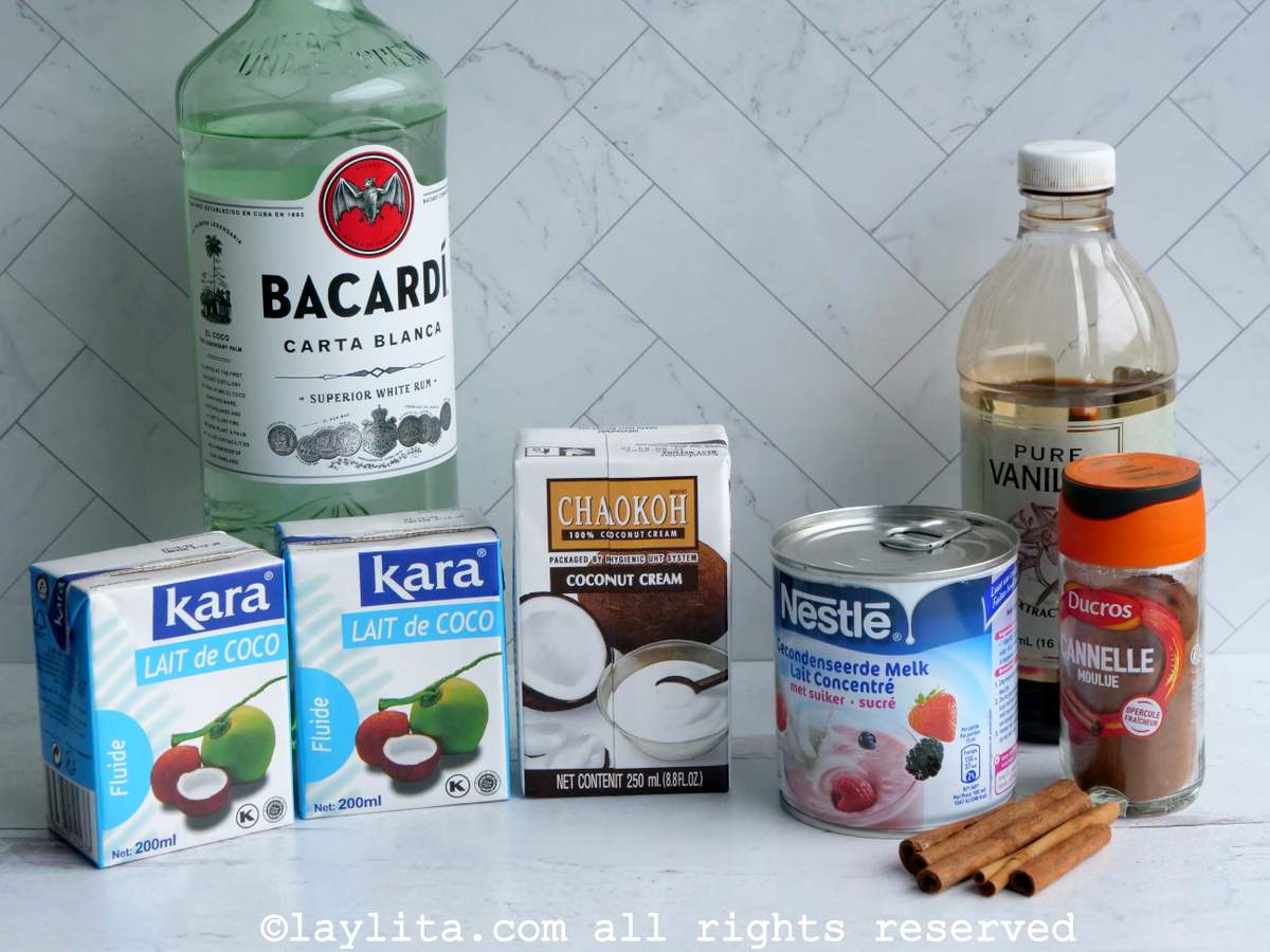 Coconut cream, coconut milk, condensed milk, rum and cinnamon on a white kitchen counter