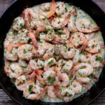 Camarones al ajillo topped with fresh chopped parsley in a skillet