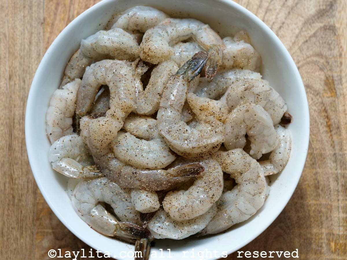 Raw shrimp seasoned in a large mixing bowl