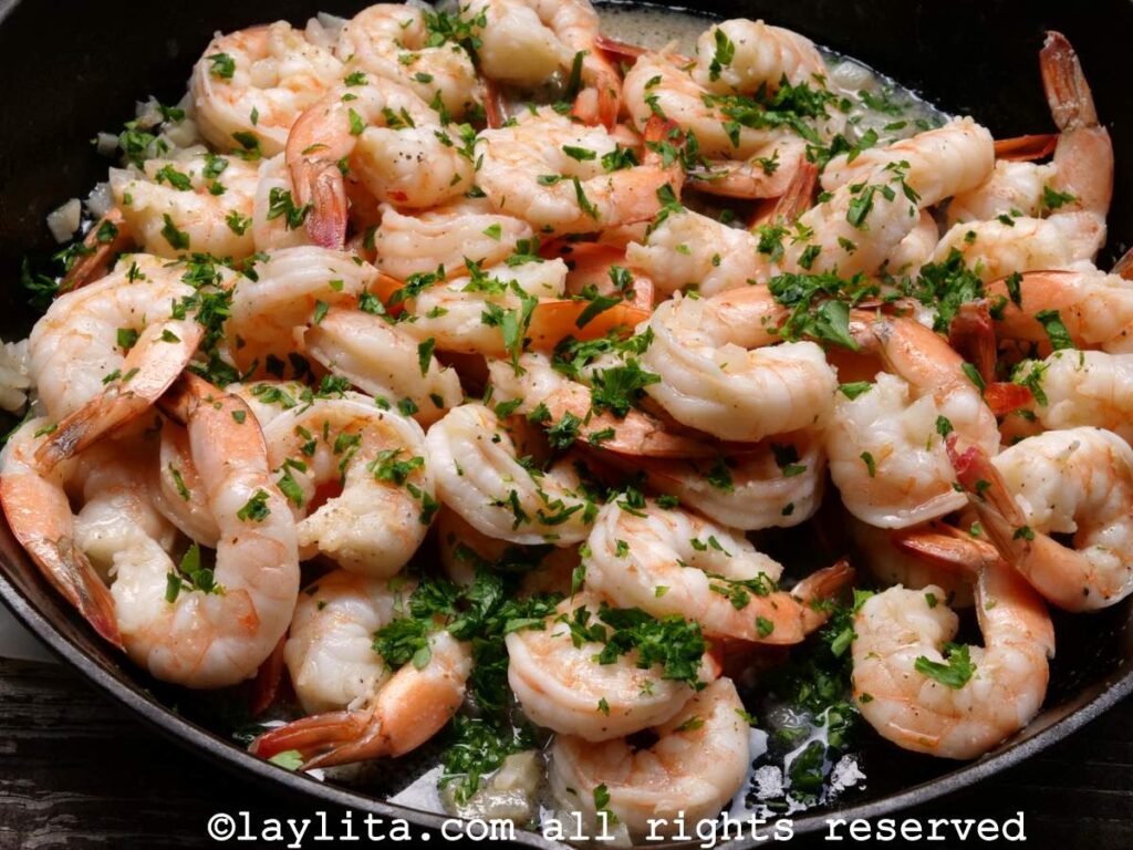 Parsley sprinkled on top of the shrimp in the skillet.